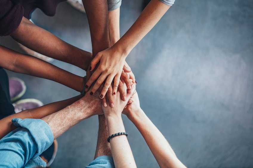 Overhead view of a group of people joining hands in support.