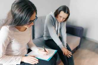 Teenage girl sitting on a couch talking to a counsellor.