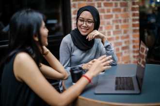 two girls sitting a a computer smiling