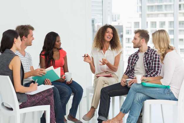 Woman leading a group of people in a therapy session.